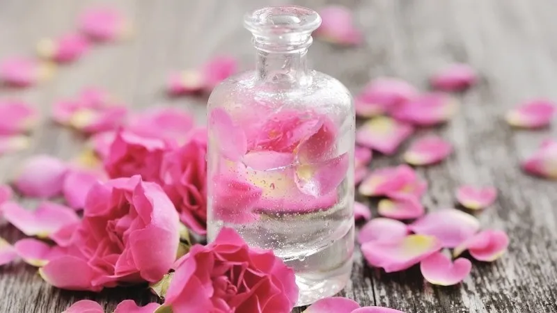 Cánh hoa hồng tươi cùng lọ xịt khoáng handmade, biểu tượng cho khả năng làm dịu và phục hồi làn da.