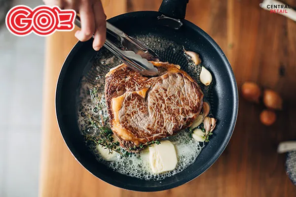 Áp chảo thịt bò bít tết trên chảo nóng với bơ và tỏi