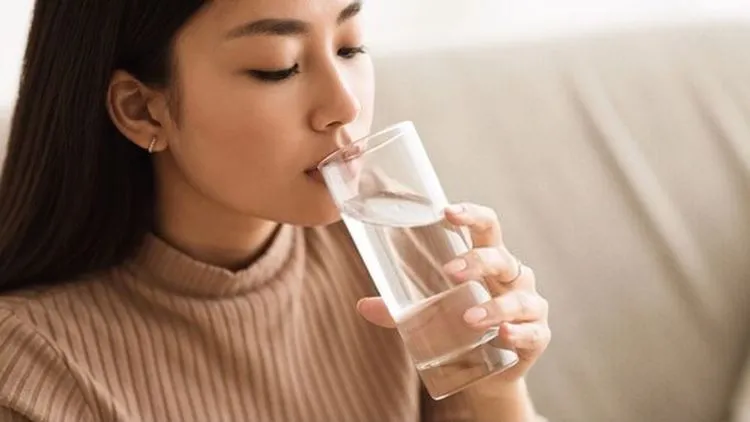 Cốc nước khoáng Thạch Bích đặt cạnh bữa ăn, minh họa thói quen uống đủ nước khoa học mỗi ngày