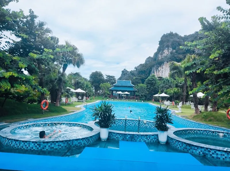 Người phụ nữ thư giãn ngâm mình trong làn nước ấm tại suối khoáng nóng Kênh Gà, bao quanh bởi khung cảnh núi non Ninh Bình yên bình