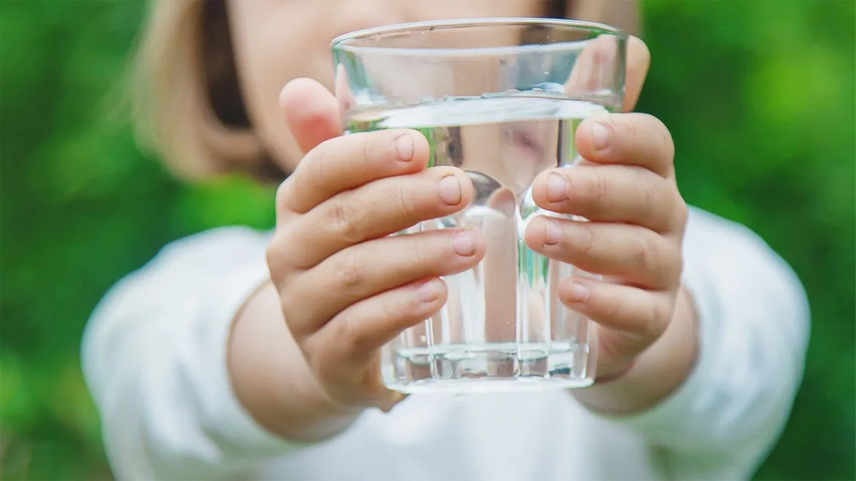 Một tay đang cầm chai nước và cân để minh họa quy đổi 1 lít bằng bao nhiêu kg